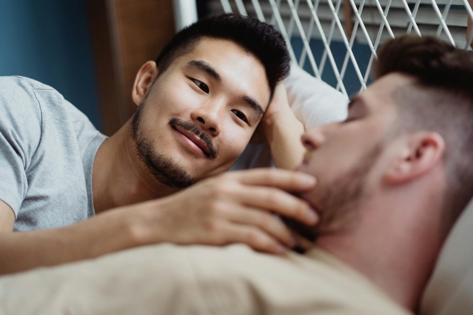 A man laying on the bed with another man.