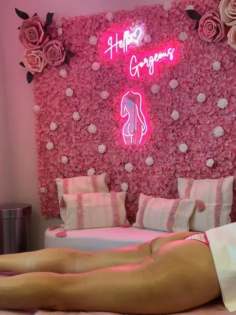 A woman laying on her stomach in front of a pink wall.