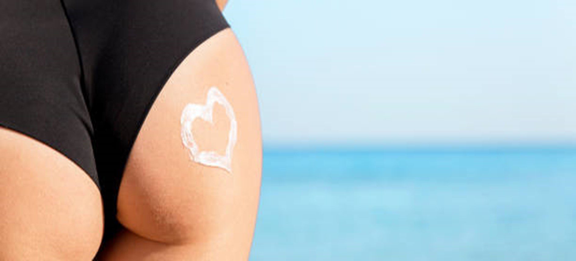 A woman with a heart shaped sunscreen on her arm.
